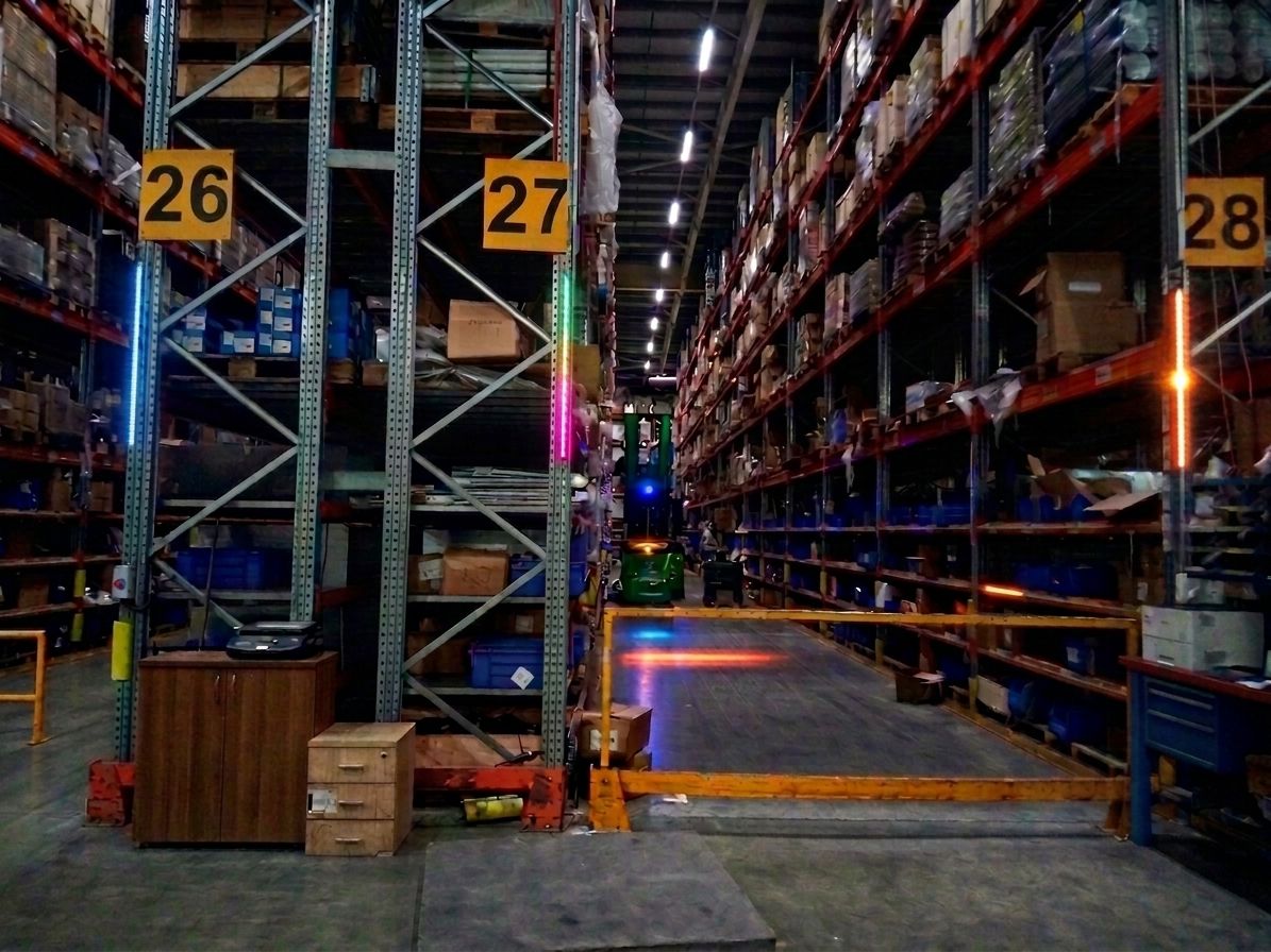 Wide warehouse aisle with multi-color LEDs lighting pallet rack locations