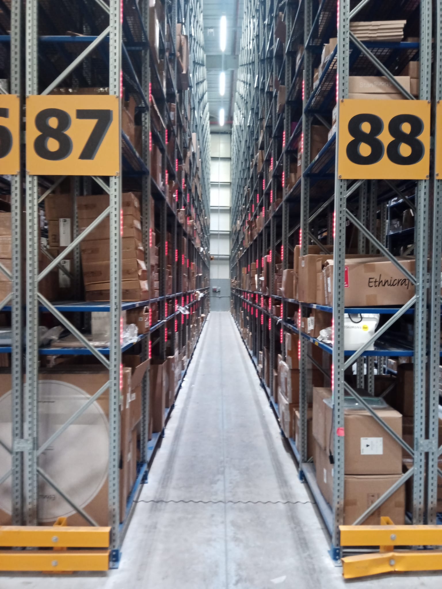 Tall pallet rack aisle with vertical red LED strips