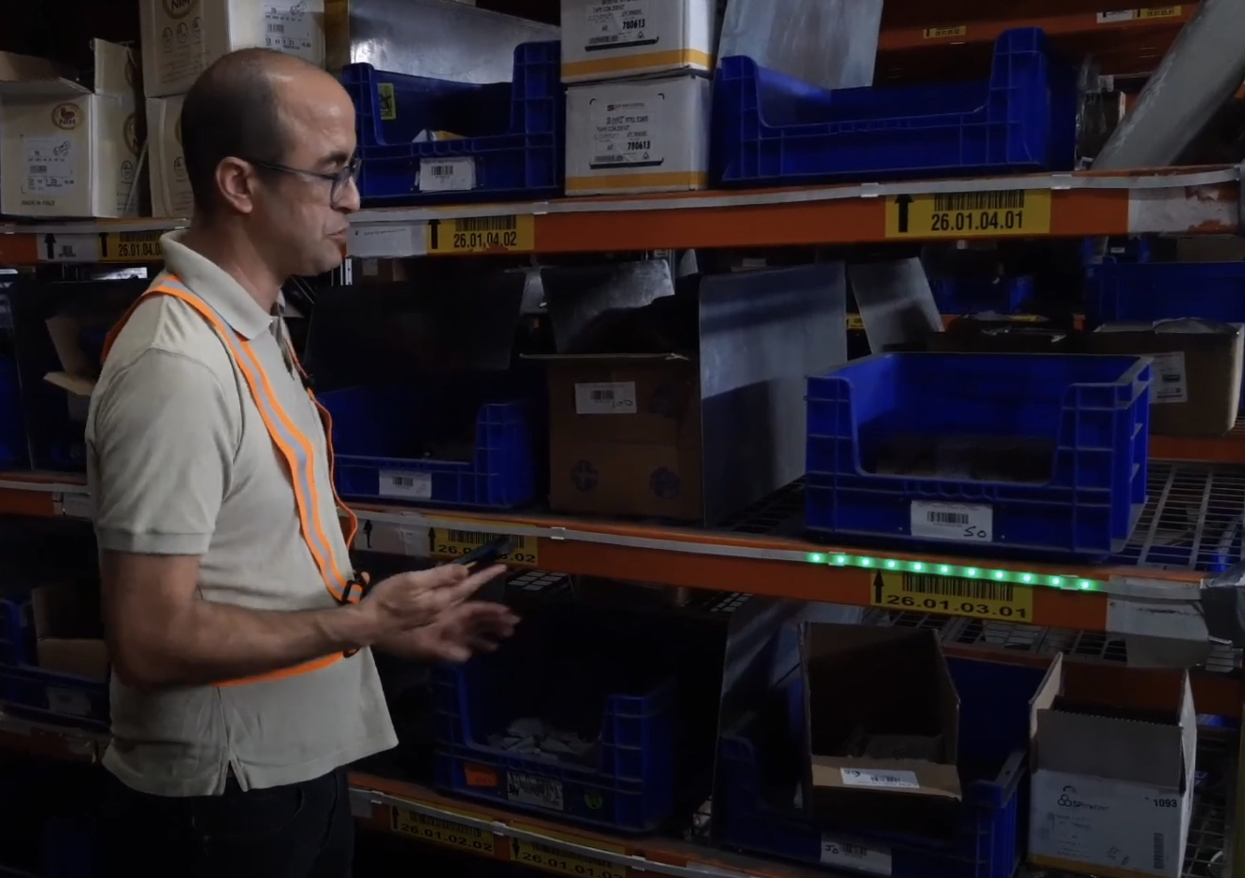 Operator picking from a parts bin shelf with a green LED indicator lit